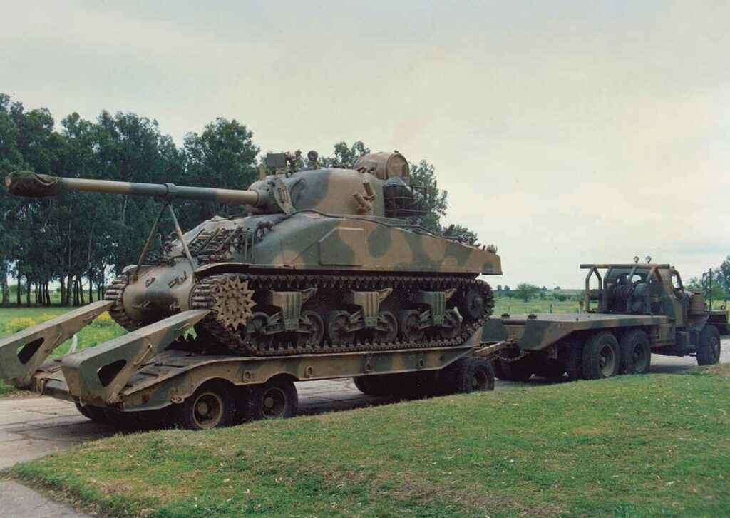 Sherman Repotenciado del Regimiento Caballería de Tanques 1 sobre carretón de transporte, remolcado por un tractor Mack B80 en 1989. Repotenciado hecho sobre la base de un Firefly Ic Hybrid; incorpora el tanque
auxiliar montado y asegurado por flejes sobre la caja de equipo de radio (Colección Juan Carlos Cicalesi).